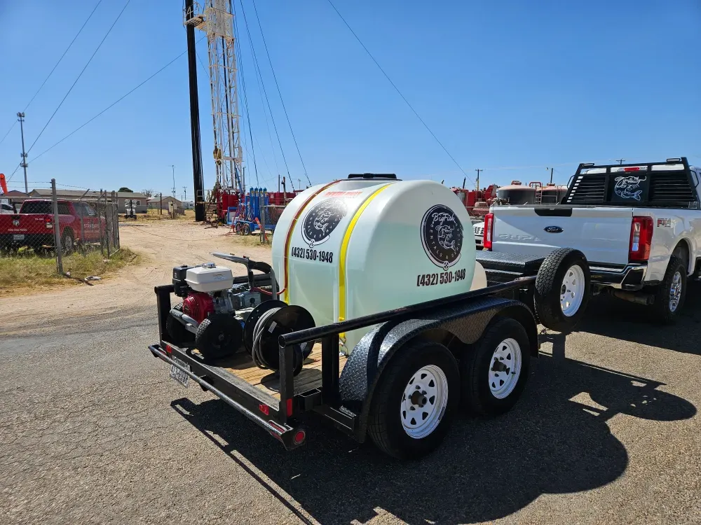 The pressure washer trailer hitched to the Big Fish Rentals pickup on a job site near Monahans, Texas, water tank, petrol pump and hose reel all mounted on the tandem axle trailer.