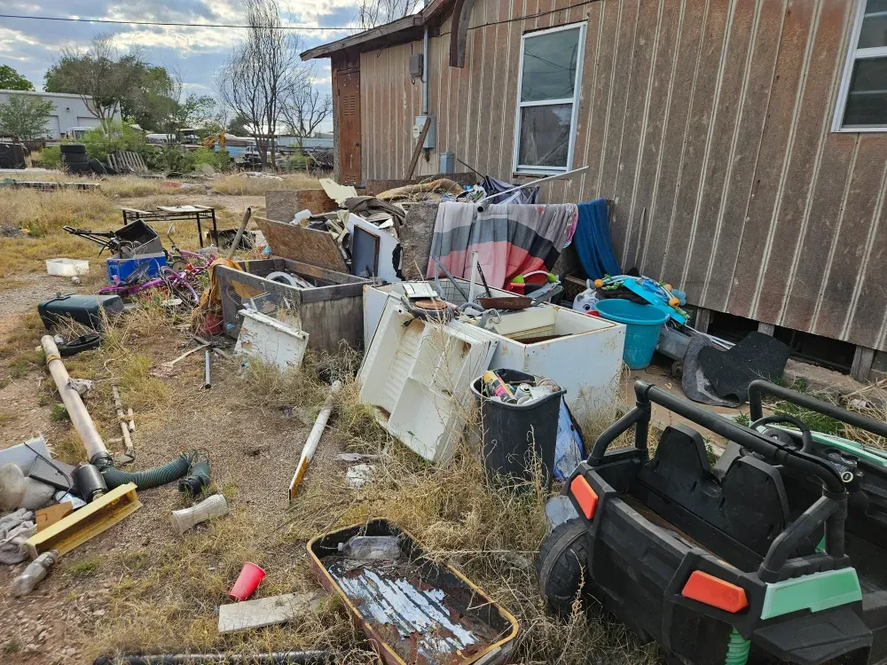Old appliances, gutted cabinets, bedding and a child's ride-on toy pulled out of a mobile home and lined up along the yard, waiting to be carried onto the truck.