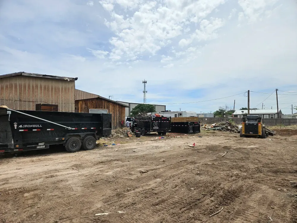 Big Fish Rentals containers of different heights lined up with a skid steer on a commercial lot in Odessa, Texas.